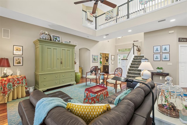 living room featuring hardwood / wood-style floors, ceiling fan, and a high ceiling