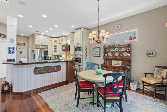 dining area with sink, dark hardwood / wood-style flooring, and a notable chandelier