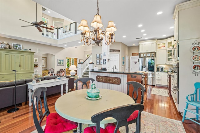 dining space featuring sink, light hardwood / wood-style floors, and ceiling fan with notable chandelier