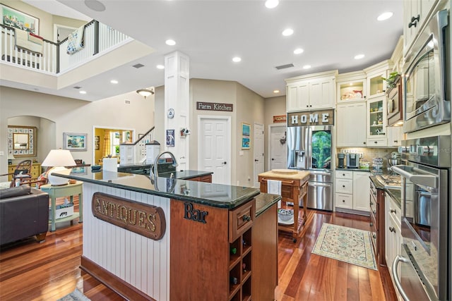 kitchen with a center island, dark hardwood / wood-style flooring, stainless steel appliances, and dark stone counters