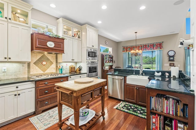 kitchen with sink, hanging light fixtures, tasteful backsplash, stainless steel appliances, and a chandelier