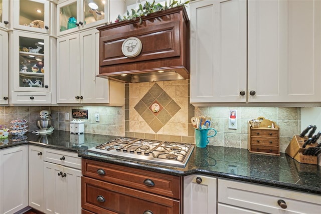 kitchen with white cabinets, stainless steel gas stovetop, dark stone counters, and tasteful backsplash