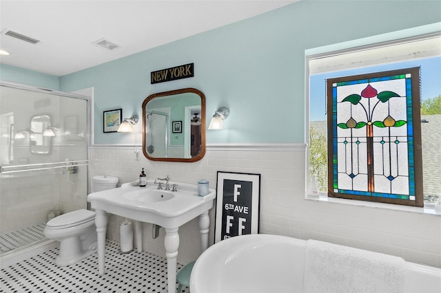 bathroom with a wealth of natural light, separate shower and tub, toilet, and tile walls