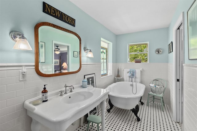 bathroom with a washtub, ceiling fan, sink, and tile walls