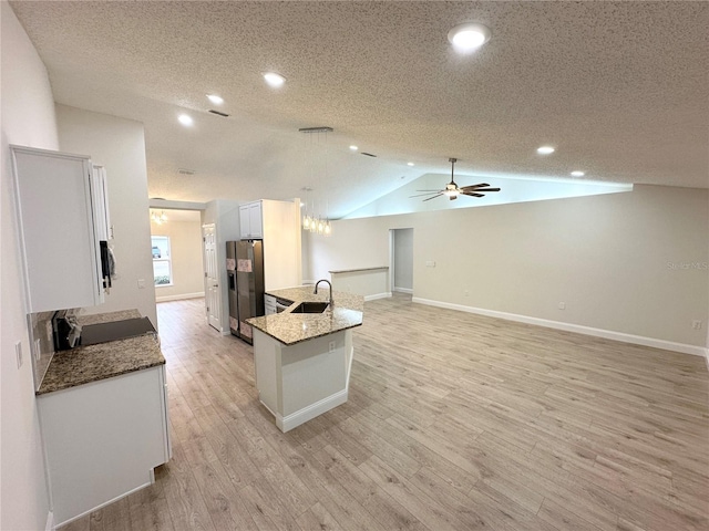 kitchen featuring white cabinets, vaulted ceiling, a textured ceiling, stone countertops, and stainless steel fridge with ice dispenser