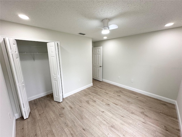 unfurnished bedroom featuring ceiling fan, light hardwood / wood-style floors, a textured ceiling, and a closet