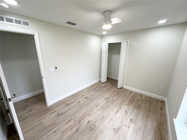 unfurnished bedroom featuring ceiling fan, light wood-type flooring, a textured ceiling, and a closet