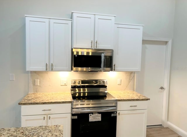 kitchen featuring white cabinets, light stone countertops, stainless steel appliances, and light hardwood / wood-style flooring