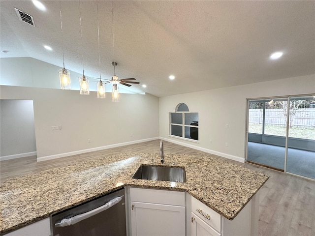 kitchen featuring sink, stainless steel dishwasher, a textured ceiling, vaulted ceiling, and white cabinets