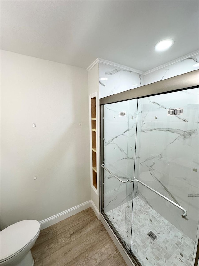 bathroom with hardwood / wood-style flooring, toilet, and a shower with door