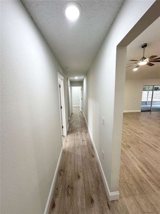 corridor featuring a textured ceiling and light wood-type flooring