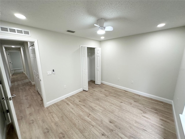 unfurnished bedroom with light wood-type flooring, a textured ceiling, a closet, and ceiling fan