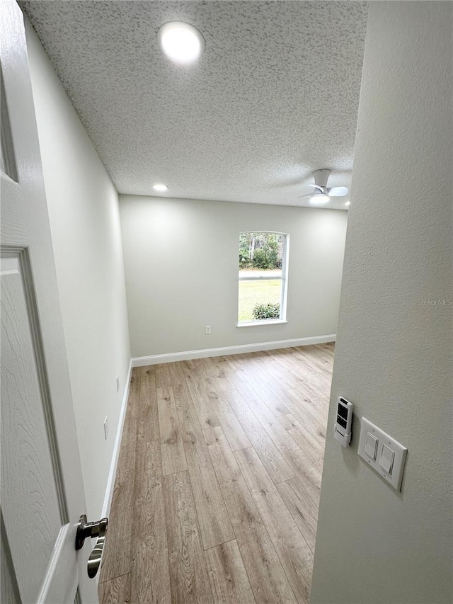 unfurnished room featuring ceiling fan, light hardwood / wood-style floors, and a textured ceiling