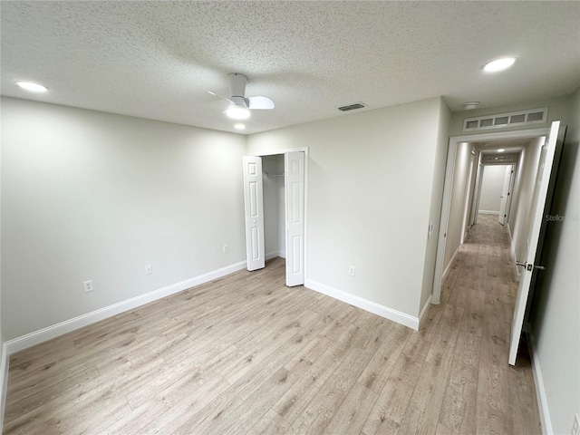 unfurnished bedroom featuring a closet, a textured ceiling, light hardwood / wood-style floors, and ceiling fan