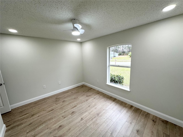 empty room featuring ceiling fan, a textured ceiling, and light hardwood / wood-style flooring