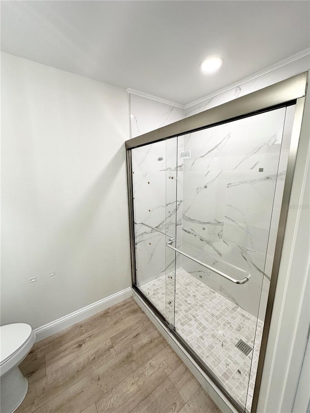 bathroom with hardwood / wood-style floors, an enclosed shower, and toilet