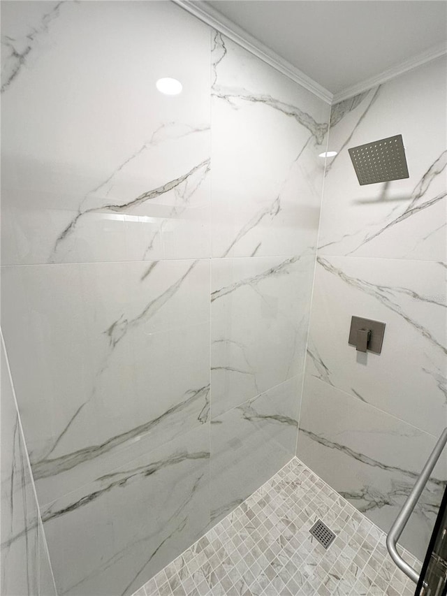 bathroom featuring a tile shower and crown molding