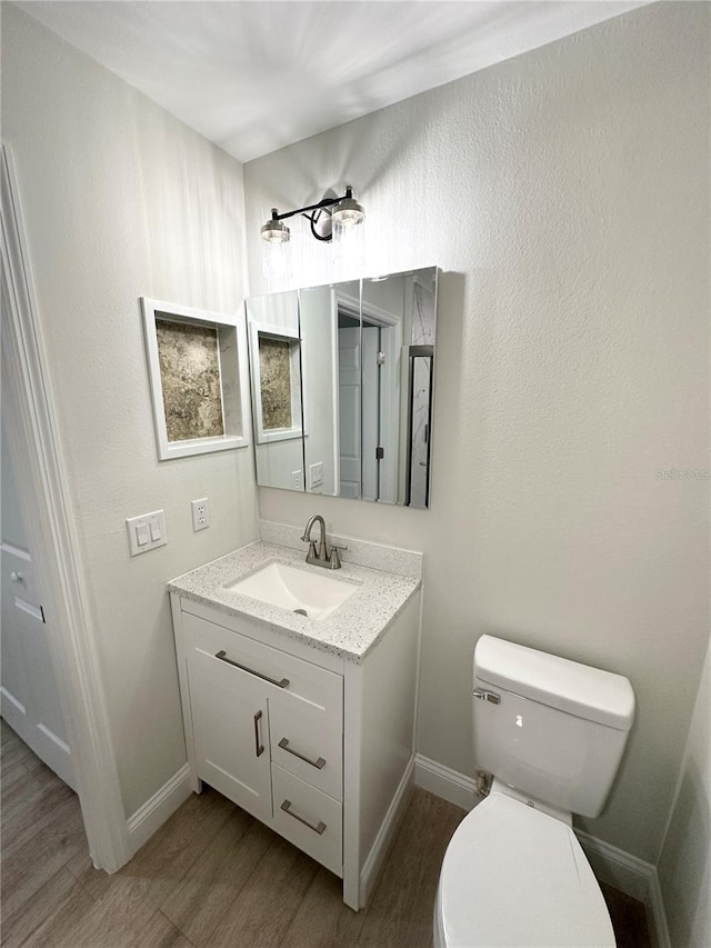 bathroom with hardwood / wood-style floors, vanity, and toilet