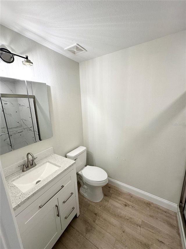 bathroom with a shower, a textured ceiling, toilet, vanity, and hardwood / wood-style flooring