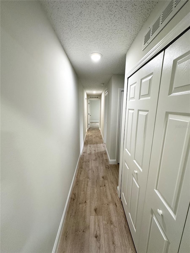 hall with light hardwood / wood-style flooring and a textured ceiling