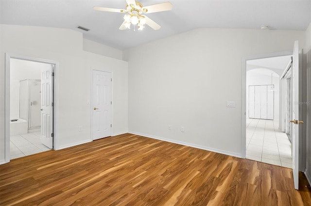 unfurnished bedroom with ceiling fan, light wood-type flooring, connected bathroom, and vaulted ceiling