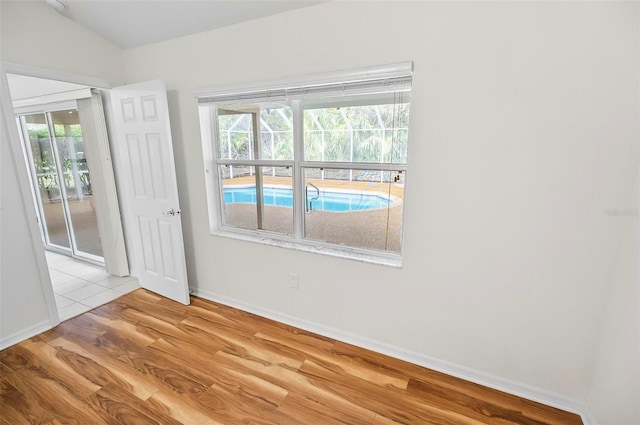 spare room with a wealth of natural light, light hardwood / wood-style floors, and vaulted ceiling