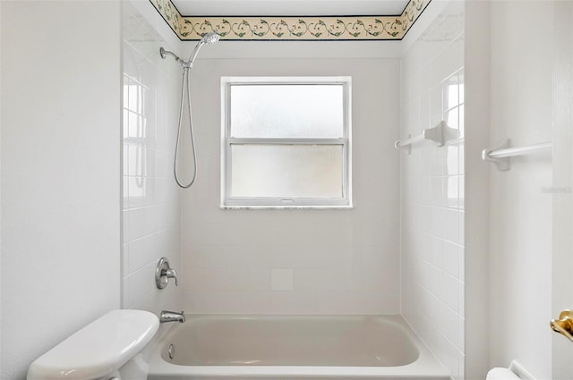 bathroom with tiled shower / bath combo and toilet