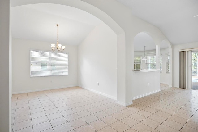 spare room with vaulted ceiling, a notable chandelier, and light tile patterned flooring