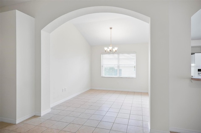 tiled spare room featuring an inviting chandelier