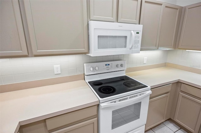 kitchen featuring light tile patterned floors, white appliances, light brown cabinets, and backsplash