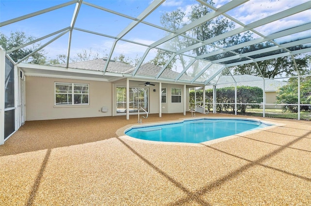 view of pool with glass enclosure, a patio area, and ceiling fan