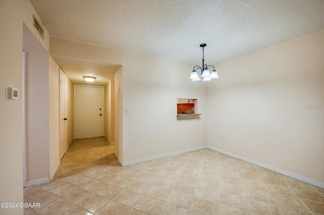 empty room with a chandelier and a textured ceiling