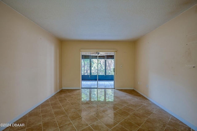 tiled spare room featuring a textured ceiling