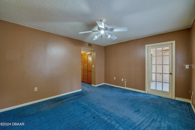 empty room featuring a textured ceiling, dark carpet, and ceiling fan