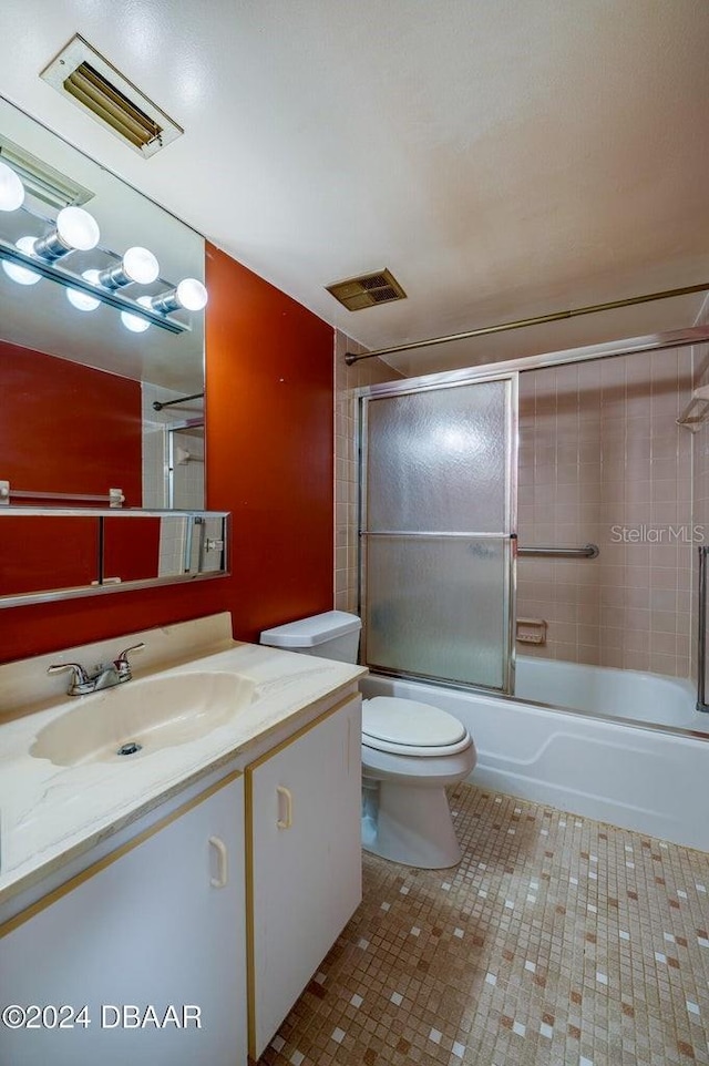 full bathroom featuring shower / bath combination with glass door, vanity, toilet, and tile patterned flooring