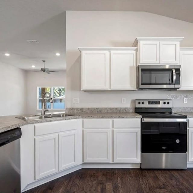 kitchen with lofted ceiling, sink, stainless steel appliances, white cabinets, and dark hardwood / wood-style flooring