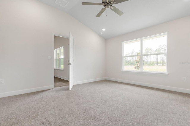 empty room with visible vents, plenty of natural light, carpet flooring, and vaulted ceiling