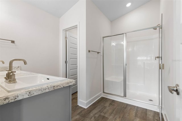 full bathroom with baseboards, wood finished floors, a sink, and a shower stall