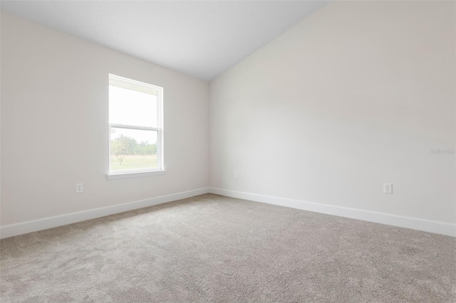 empty room with lofted ceiling, carpet floors, and baseboards