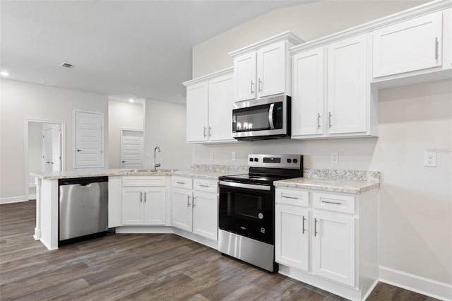 25 Port Echo Ln, Palm Coast, FL 32164 - kitchen with stainless steel appliances, a peninsula, white cabinets, dark wood finished floors, and recessed lighting