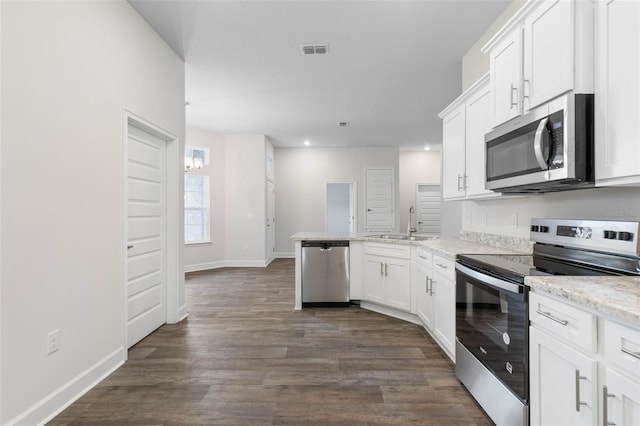 25 Port Echo Ln, Palm Coast, FL 32164 - kitchen with appliances with stainless steel finishes, a peninsula, white cabinets, dark wood finished floors, and recessed lighting