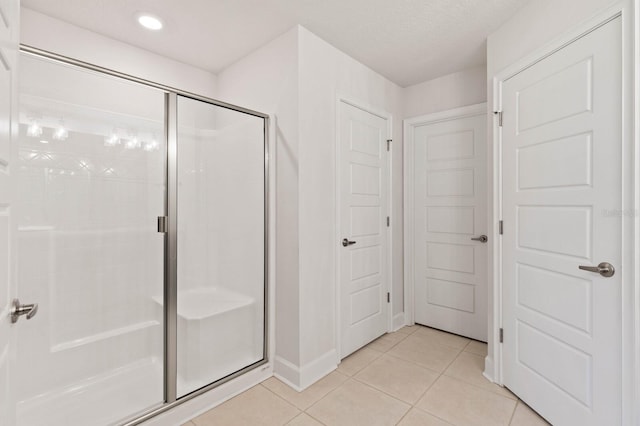 bathroom with a shower with shower door and tile patterned flooring