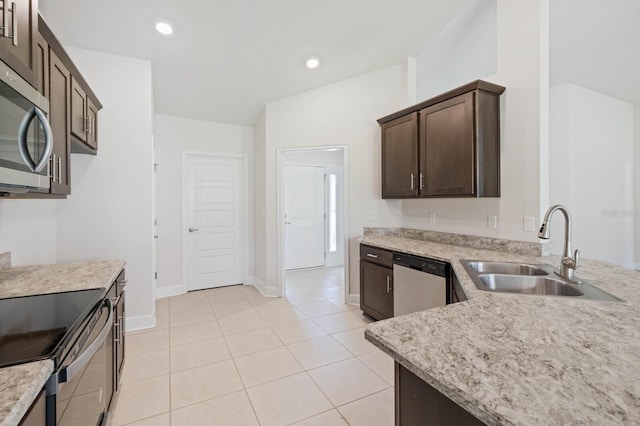 kitchen with sink, dark brown cabinets, stainless steel appliances, light stone counters, and light tile patterned flooring