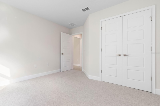 unfurnished bedroom featuring light colored carpet and a closet