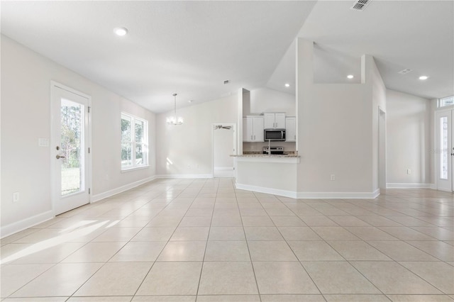 unfurnished living room with vaulted ceiling, light tile patterned flooring, and an inviting chandelier