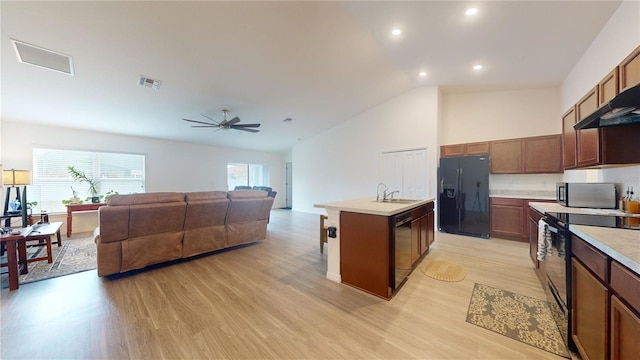 kitchen featuring ceiling fan, sink, an island with sink, light hardwood / wood-style floors, and black appliances