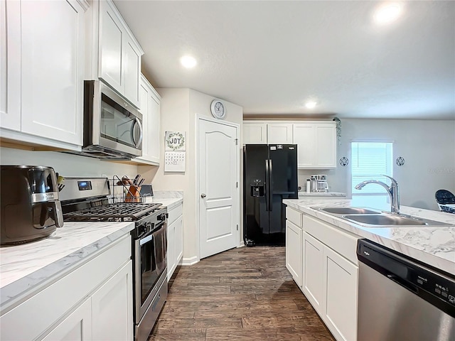 kitchen with white cabinets, sink, light stone counters, dark hardwood / wood-style flooring, and stainless steel appliances