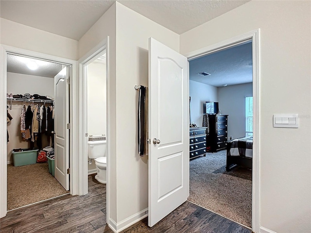 corridor with dark colored carpet and a textured ceiling