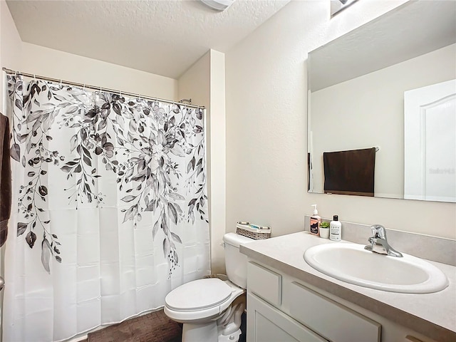 bathroom featuring hardwood / wood-style flooring, vanity, a textured ceiling, and toilet