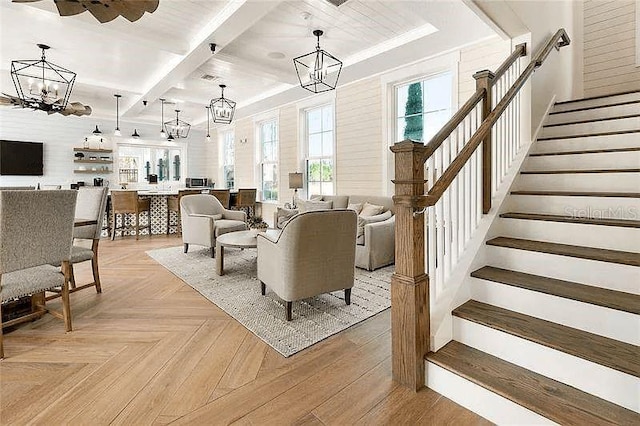 living room with beam ceiling, light parquet floors, and a notable chandelier